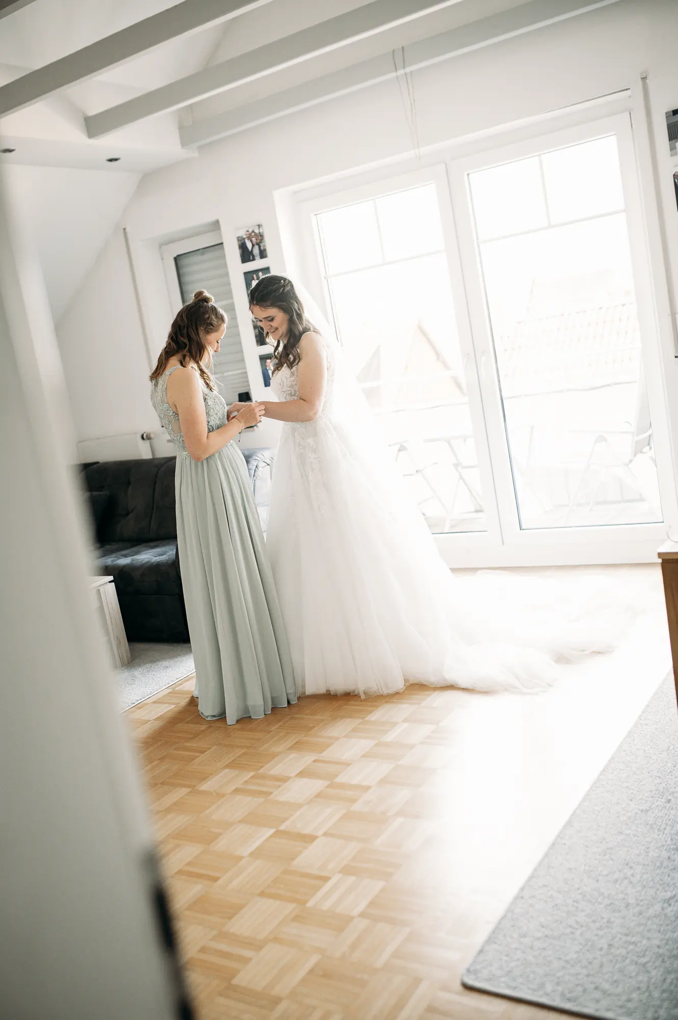 Die Trauzeugin hilft Kristin beim Anziehen des Brautkleides