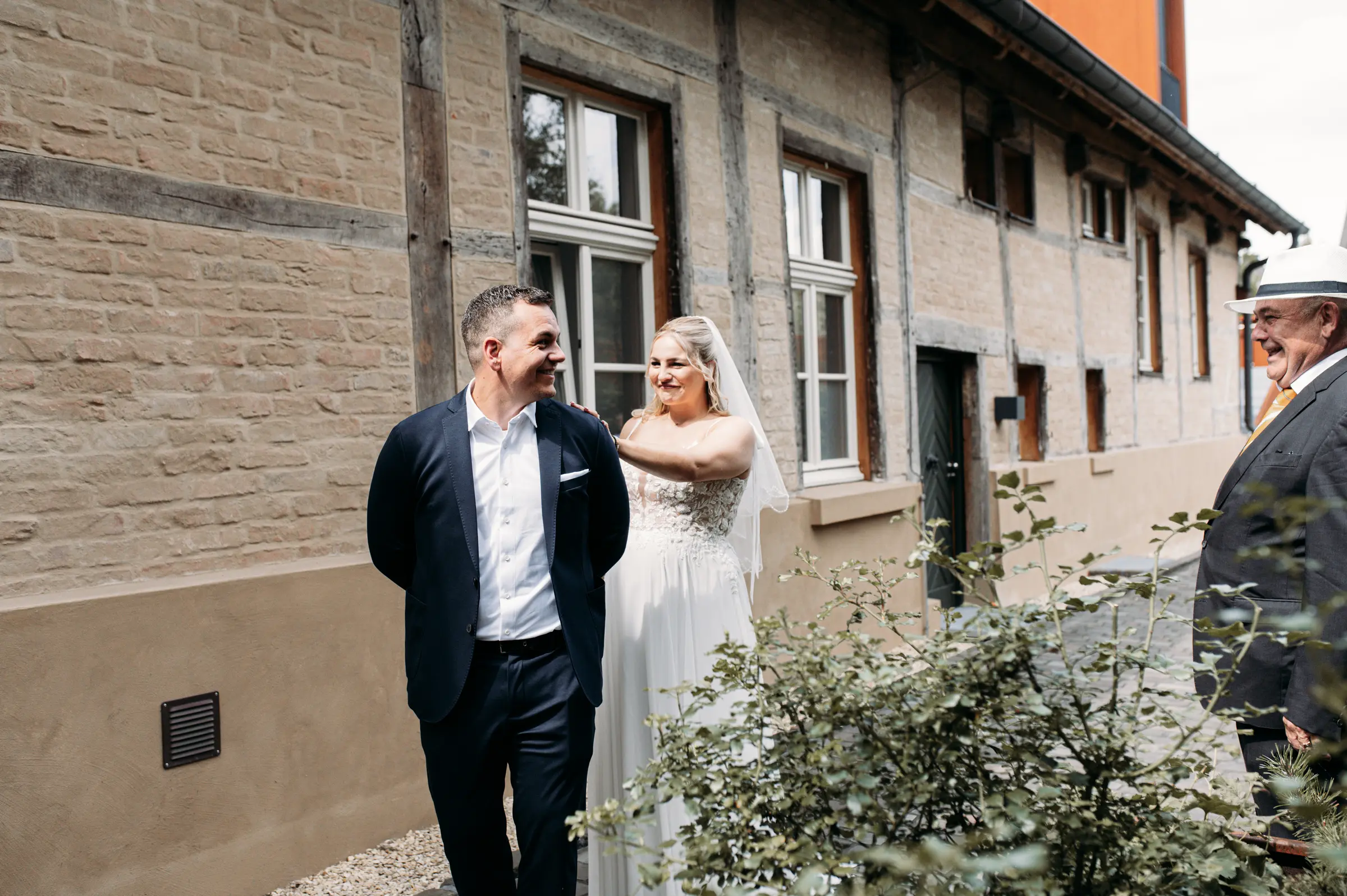 Erster gemeinsamer Moment des Brautpaares vor dem Alten Zollhaus, im Hintergrund ein lachender Gast