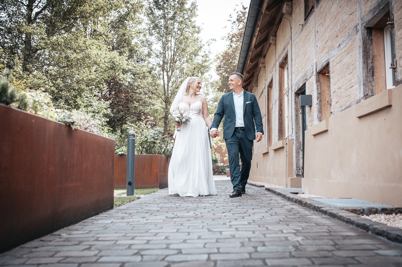 Brautpaar geht Hand in Hand an einem historischen Gebäude entlang